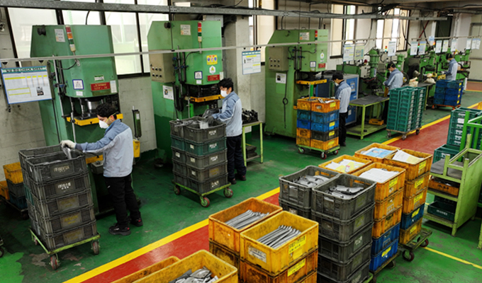 Workers assigned to operate riveting machines lined up in a row, one worker per machine at Dawoo Technology