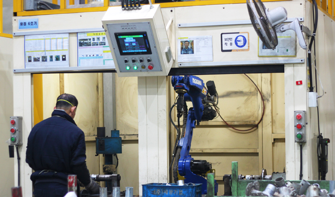 The back view of a worker handling robotic welding at Dawoo Technology's welding factory